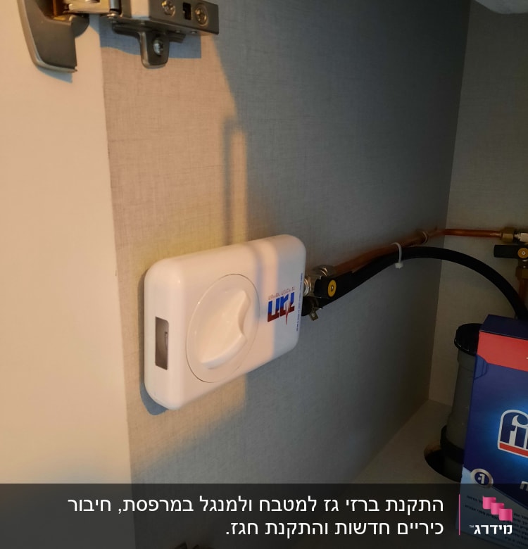 מכשיר גז לבן מותקן על קיר עם צינור מחובר